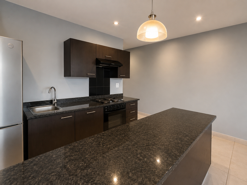 Modern kitchen featuring dark wood cabinetry, granite countertops, built-in oven, electric hob, and a functional breakfast bar island.