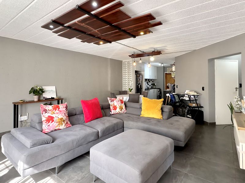 Open plan living area featuring tiled flooring, a unique decorative timber ceiling element with integrated lighting, and a seamless flow to the kitchen.