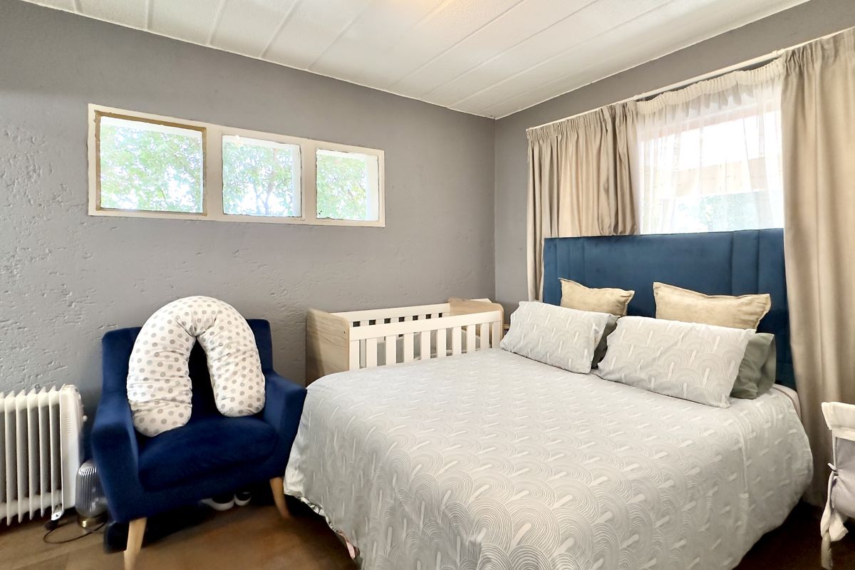 A bedroom featuring textured grey walls, a panelled ceiling, and a built-in radiator, offering a functional space with natural light from multiple windows.