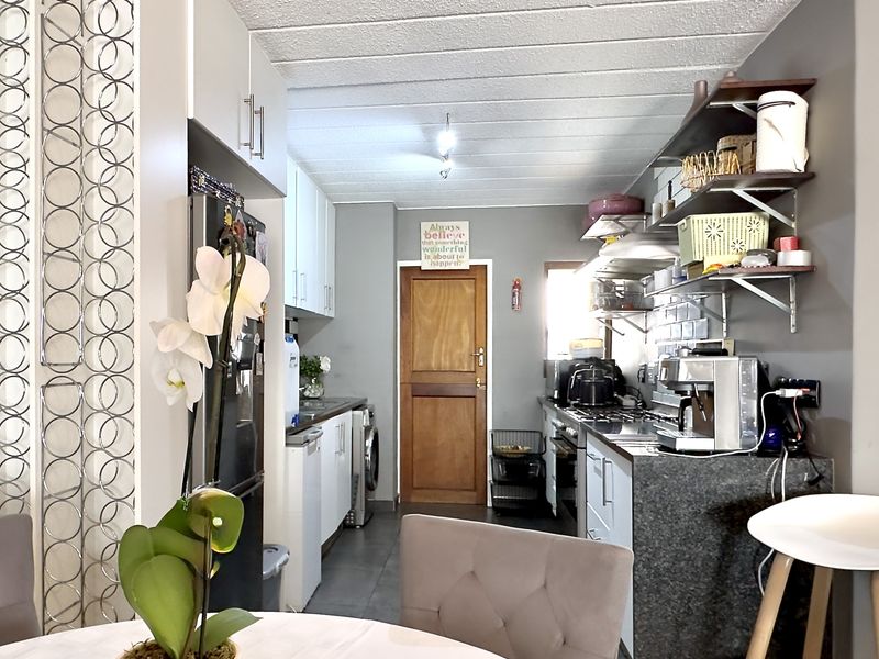 A functional kitchen featuring granite countertops, built-in cabinetry, open shelving, and integrated laundry facilities, offering a practical layout for daily use.