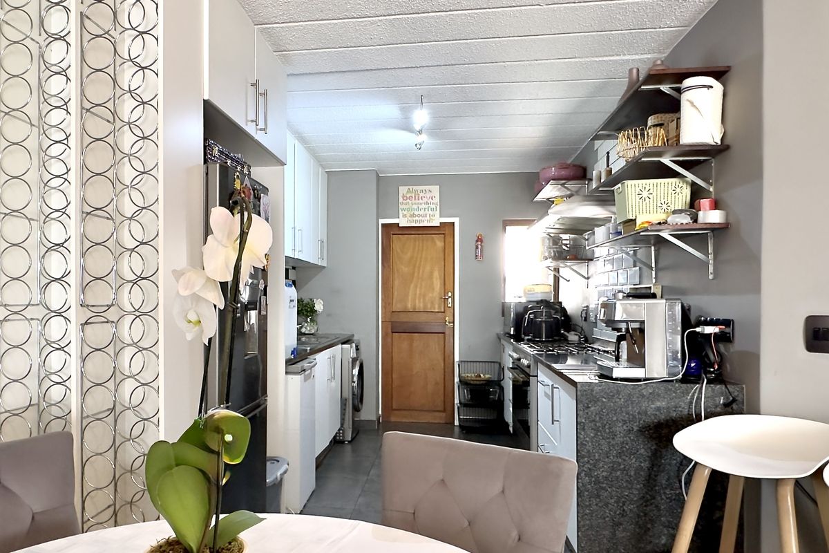 A functional kitchen featuring granite countertops, built-in cabinetry, open shelving, and integrated laundry facilities, offering a practical layout for daily use.