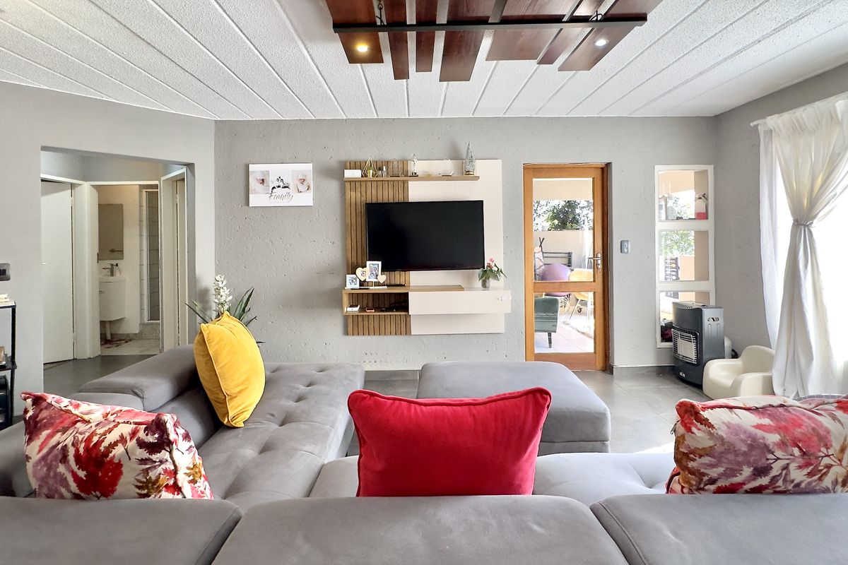 Spacious living room featuring a modern built-in media unit, unique timber ceiling detail, and direct access to an outdoor patio area.