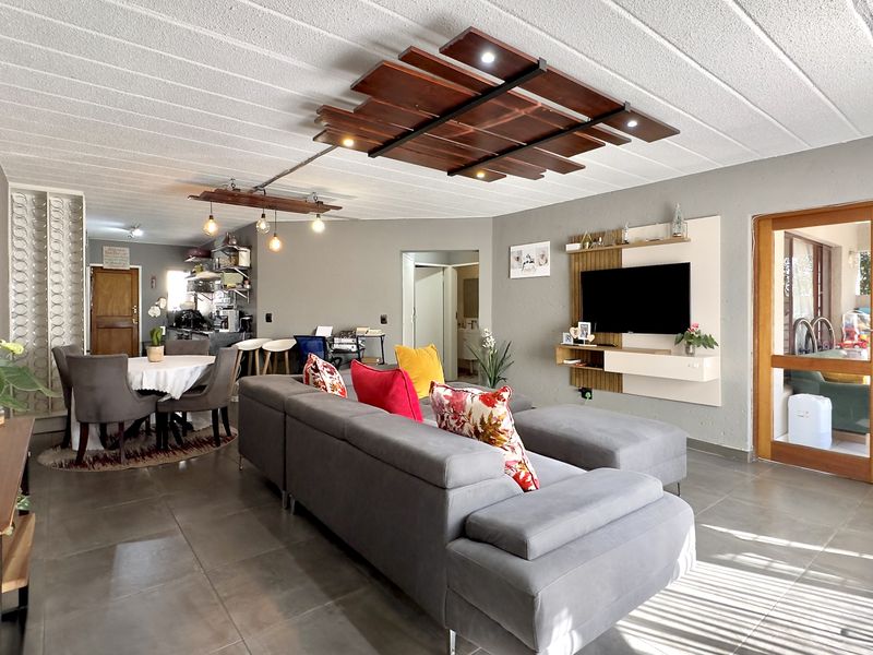 Spacious open-plan living and dining area featuring tiled floors, a decorative timber ceiling feature, and a built-in media console.