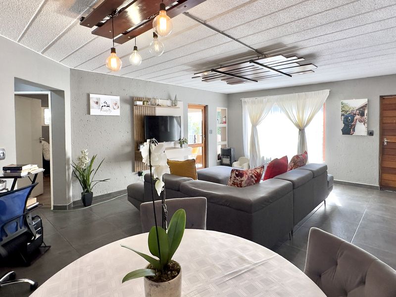 Spacious open-plan living area featuring tiled flooring, a textured ceiling, and a built-in media unit, creating a comfortable and functional living space.