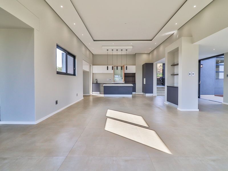 Spacious open-plan living and kitchen area featuring modern cabinetry, recessed ceiling lighting, and large format floor tiles, offering a clean and contemporary aesthetic.