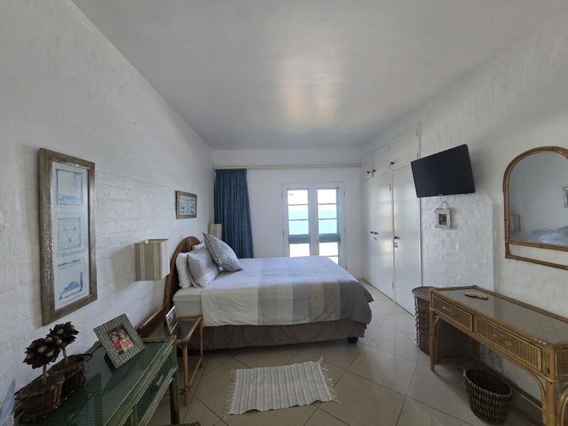 A bedroom featuring built-in cupboards, tiled flooring, and glass doors leading to an outdoor area with a view.