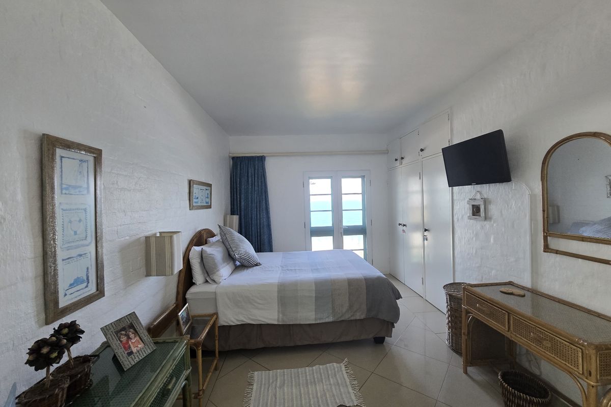 A bedroom featuring built-in cupboards, tiled flooring, and glass doors leading to an outdoor area with a view.