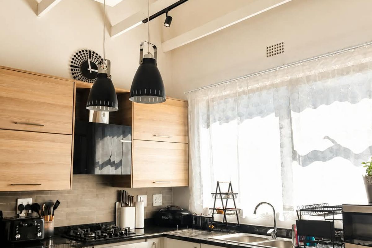 Modern kitchen featuring light wood and white cabinetry, granite countertops, gas hob, built-in oven, and striking exposed timber ceiling beams.