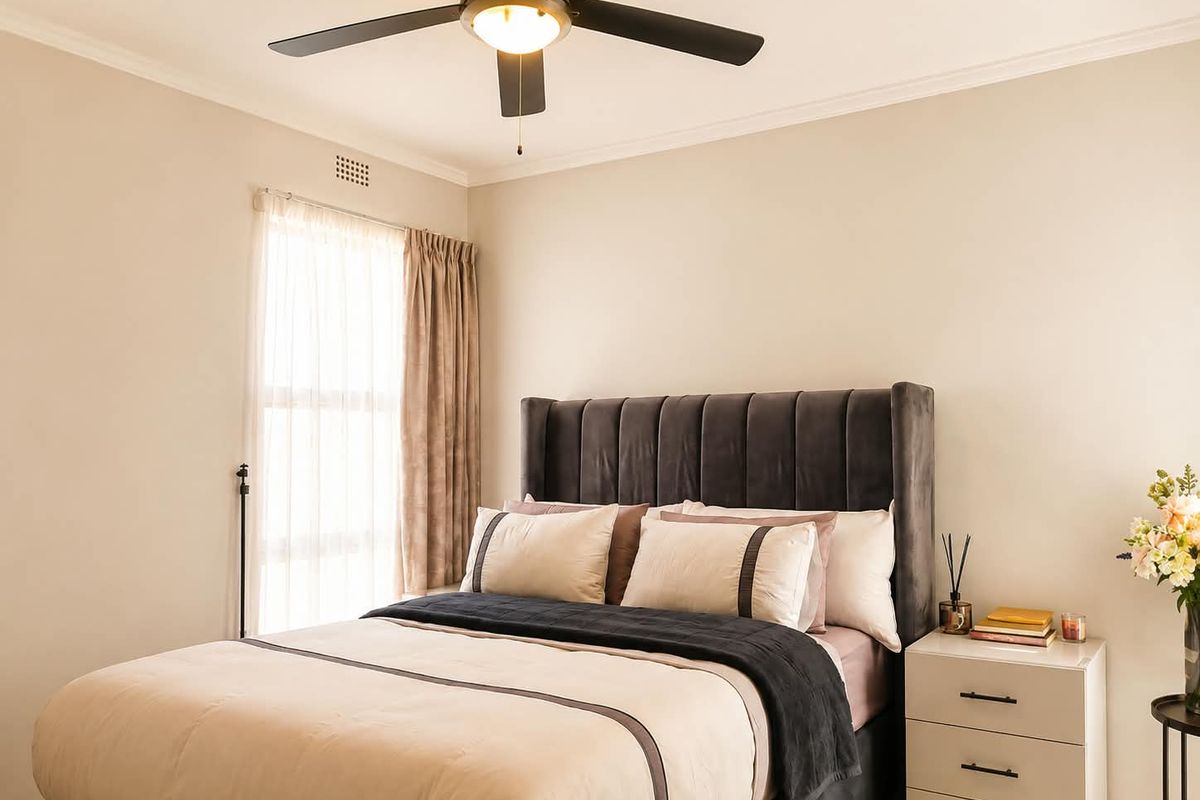 A well-maintained bedroom featuring a central ceiling fan, crown molding, and neutral wall finishes, providing a comfortable and inviting living space.