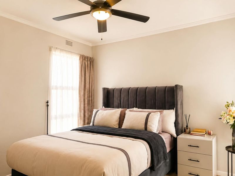 A well-maintained bedroom featuring a central ceiling fan, crown molding, and neutral wall finishes, providing a comfortable and inviting living space.