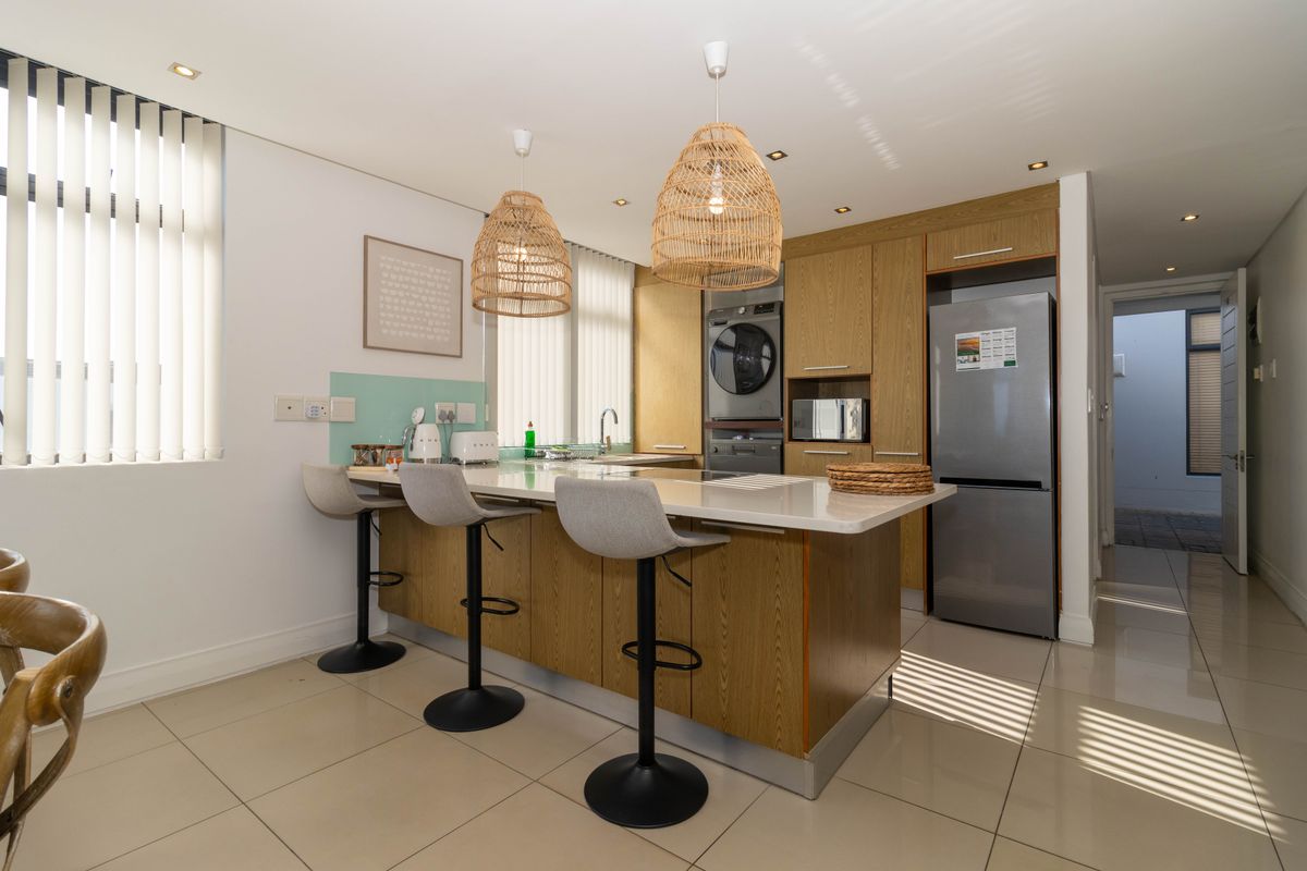 Modern kitchen featuring a central island with stone countertops, built-in cabinetry, integrated appliances, and tiled flooring, offering a functional and contemporary cooking space.