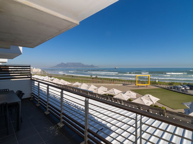 Spacious balcony featuring tiled flooring and a metal balustrade, offering panoramic ocean and mountain views.