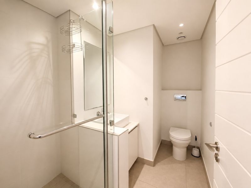 Modern bathroom featuring a glass-enclosed shower, wall-mounted toilet, and a sleek vanity with a vessel sink in a clean, minimalist design.