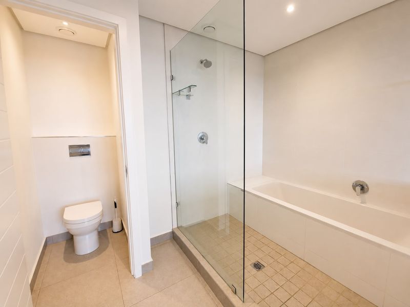Modern bathroom featuring a clean white aesthetic, a built-in bathtub, a separate glass-enclosed shower, and a wall-mounted toilet with a concealed cistern.