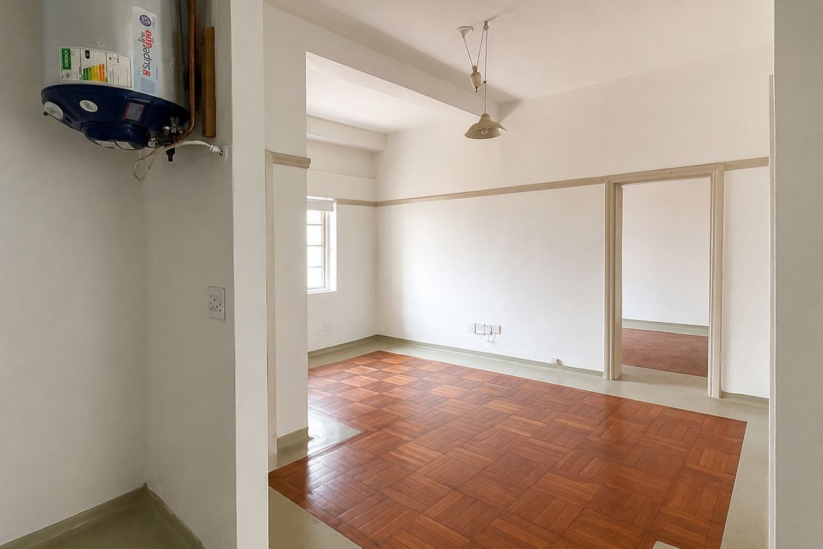 An empty living area featuring classic parquet flooring, neutral walls with picture rails, and an integrated electric water heater.