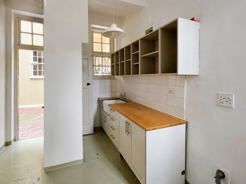 A functional scullery area featuring a butler sink, wooden countertop, and ample built-in cabinetry with direct access to an outdoor courtyard.