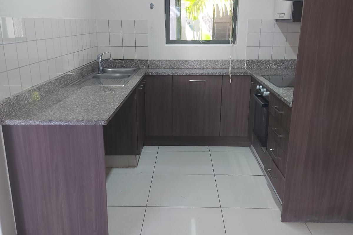 A functional U-shaped kitchen featuring granite countertops, built-in oven, hob, extractor fan, and ample cabinetry with a tiled splashback.