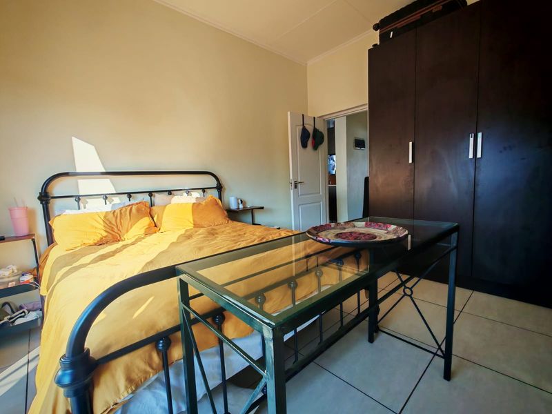 A bedroom featuring tiled flooring and a large dark built-in wardrobe, offering functional storage space.