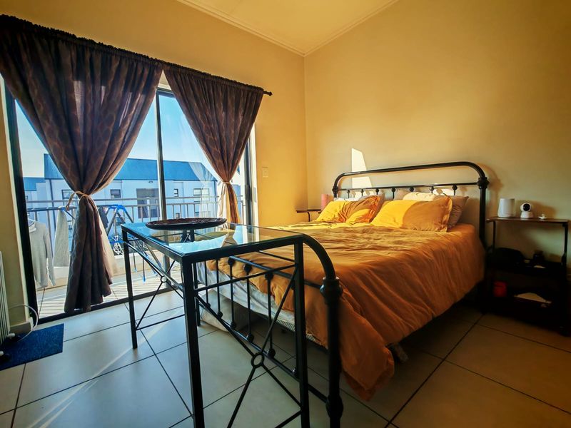 A bedroom featuring tiled flooring and a sliding glass door providing direct access to a private balcony.