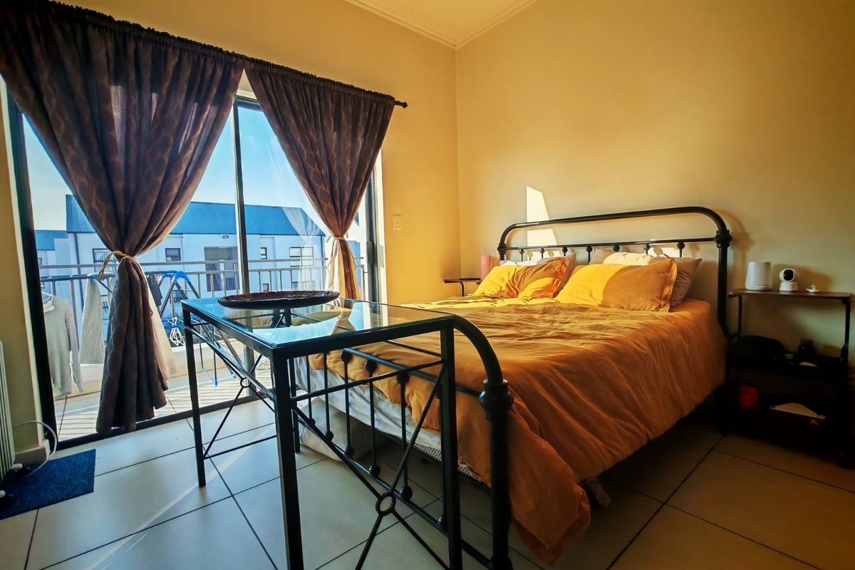 A bedroom featuring tiled flooring and a sliding glass door providing direct access to a private balcony.