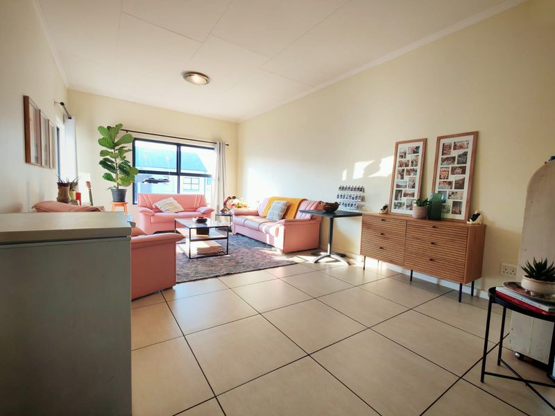 A spacious living room featuring neutral tiled flooring and large windows that provide ample natural light, creating a bright and inviting atmosphere.