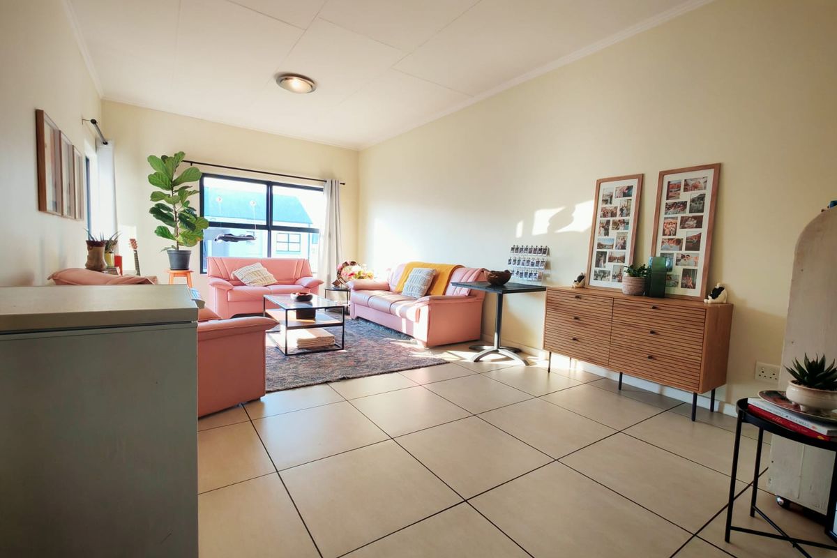 A spacious living room featuring neutral tiled flooring and large windows that provide ample natural light, creating a bright and inviting atmosphere.