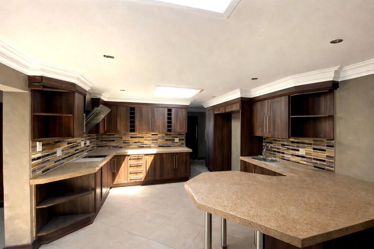 Spacious kitchen featuring dark wood cabinetry, stone countertops, mosaic tile backsplash, a breakfast bar, and a large skylight providing ample natural light.