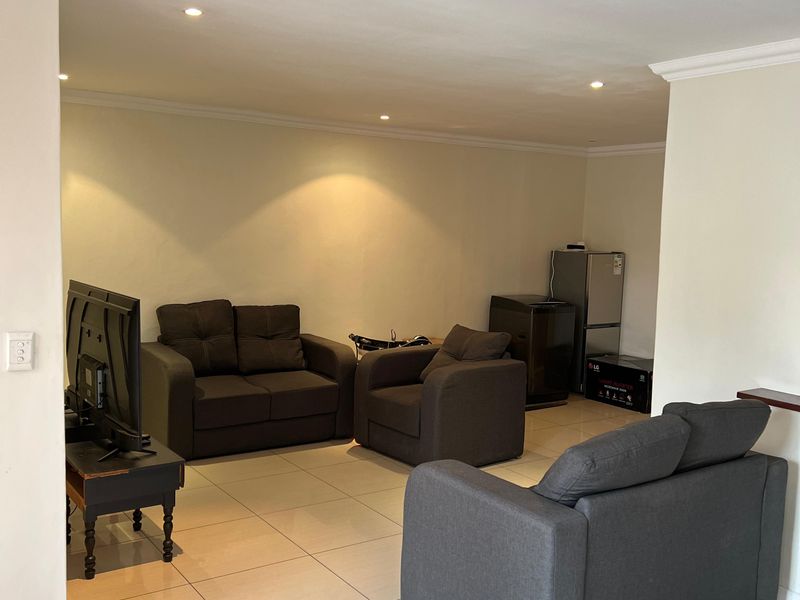 A spacious living area featuring neutral tiled flooring, recessed downlighting, and decorative coving, providing a clean and functional foundation for interior design.