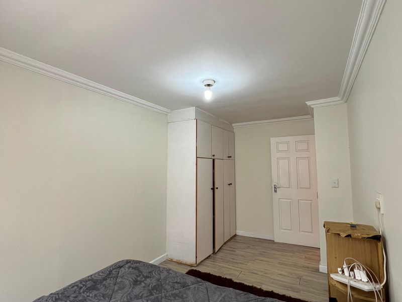 A functional bedroom featuring laminate flooring, coving, and a built-in wardrobe, offering a neutral base for personalization.