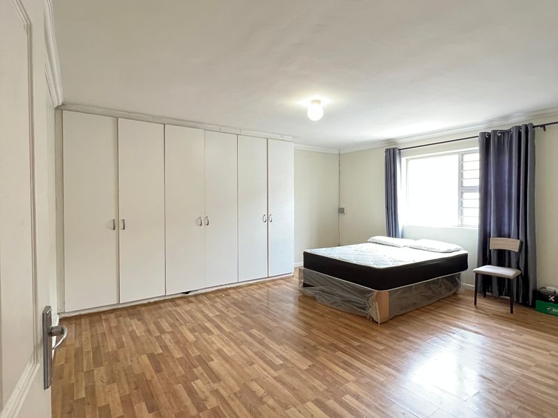 Spacious bedroom featuring extensive built-in cupboards and durable laminate flooring, offering a clean and functional layout ready for personalization.
