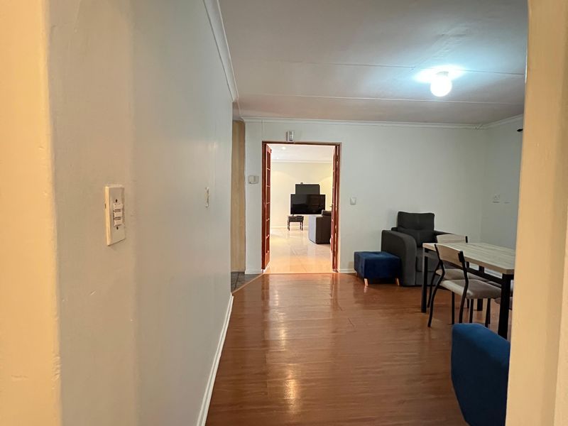 A view through an arched doorway into a living area, featuring laminate flooring and neutral wall finishes.