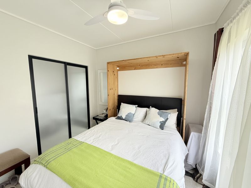A well-maintained bedroom featuring a built-in wardrobe with sliding doors and a ceiling fan, offering a clean and functional living space.