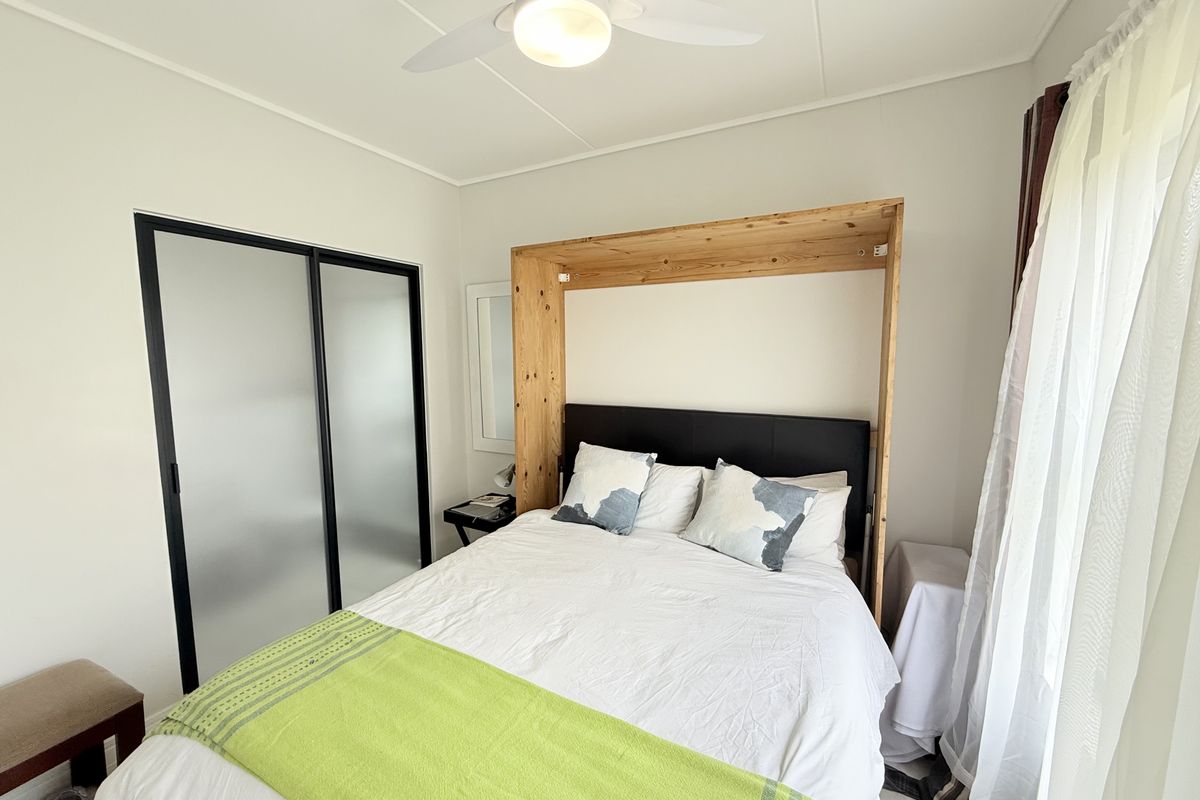 A well-maintained bedroom featuring a built-in wardrobe with sliding doors and a ceiling fan, offering a clean and functional living space.