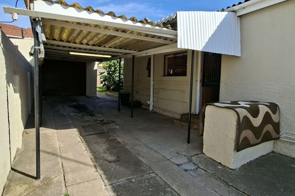 Rear exterior view featuring a covered carport area with concrete paving and direct access to the property entrance.
