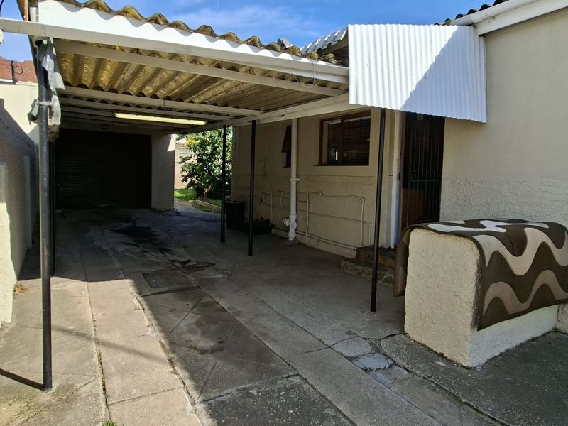 Rear exterior view featuring a covered carport area with concrete paving and direct access to the property entrance.