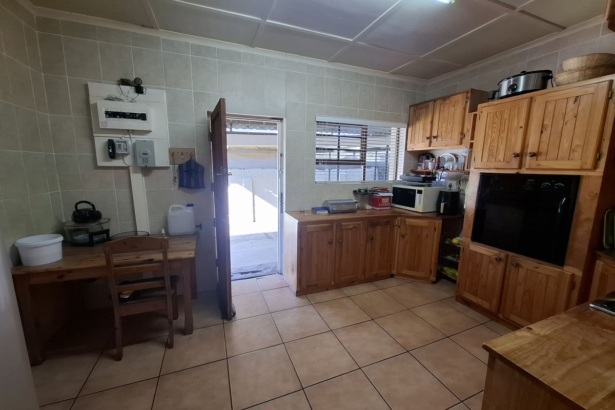 A functional kitchen featuring wooden cabinetry, tiled walls and flooring, and a built-in oven, with direct access to an outdoor area.