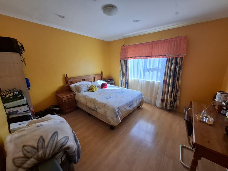 A bedroom featuring laminate flooring and bright yellow walls, offering a functional space ready for cosmetic updates and modern styling.