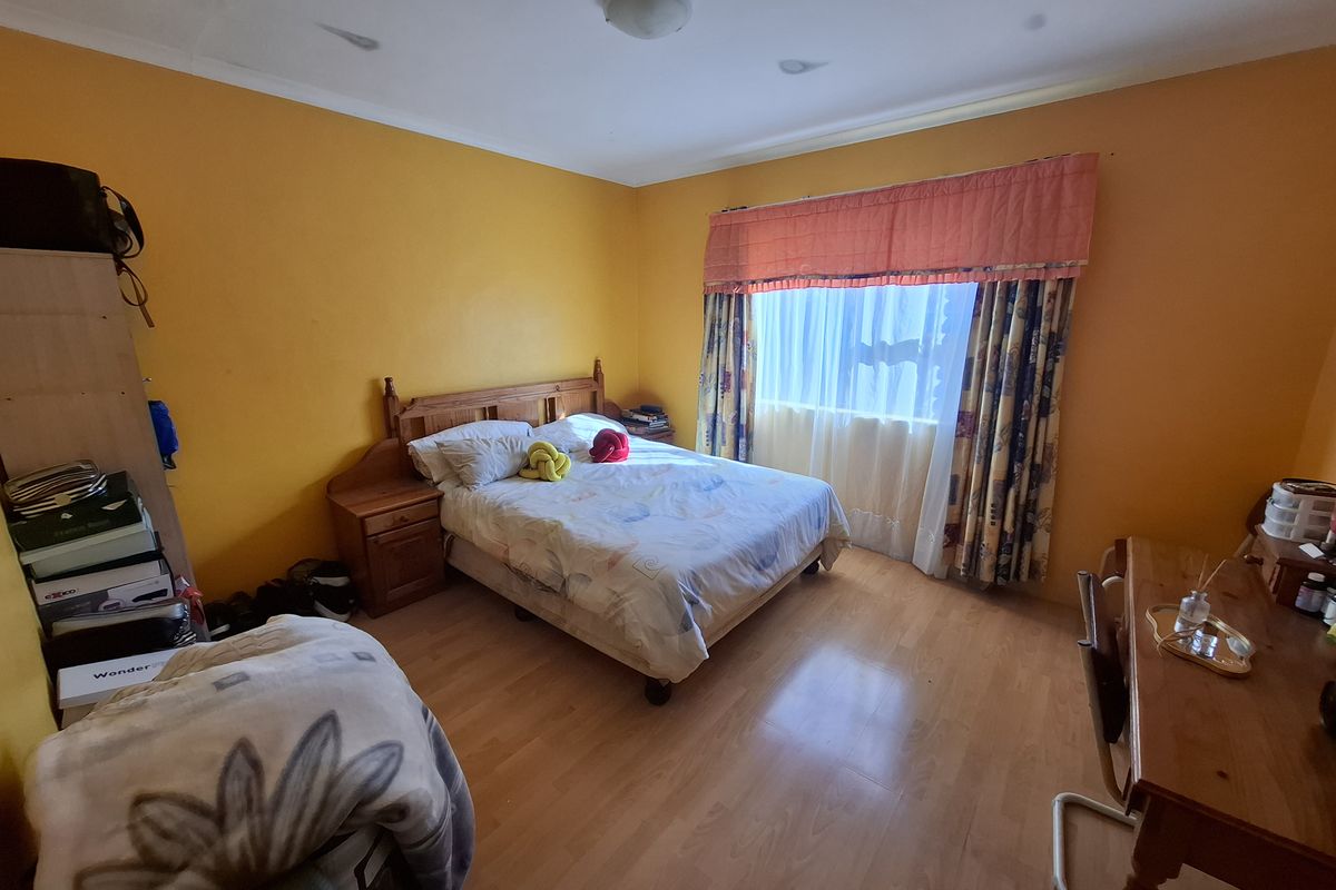 A bedroom featuring laminate flooring and bright yellow walls, offering a functional space ready for cosmetic updates and modern styling.