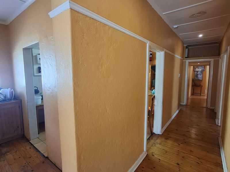A long hallway featuring original timber flooring and painted walls, connecting multiple rooms within the home.