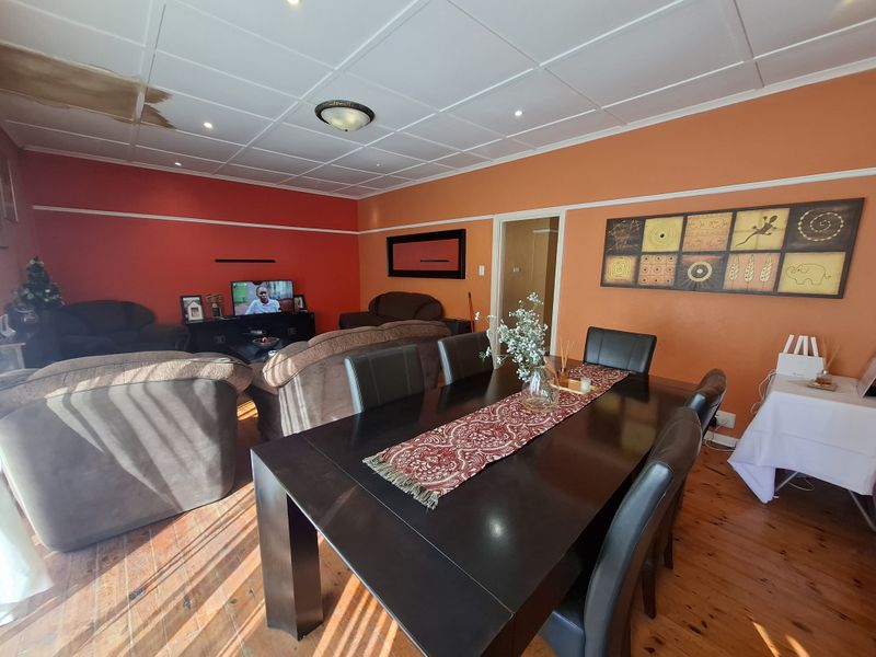 Open plan living and dining area featuring timber flooring and recessed lighting, currently showing visible water damage on the ceiling tiles.
