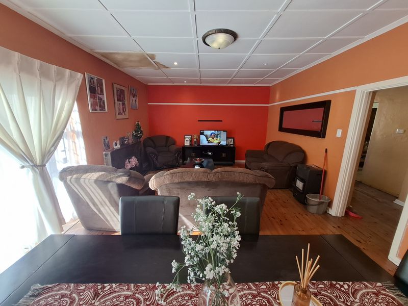 A living room featuring timber flooring and a ceiling with visible water damage, requiring maintenance and cosmetic updates.