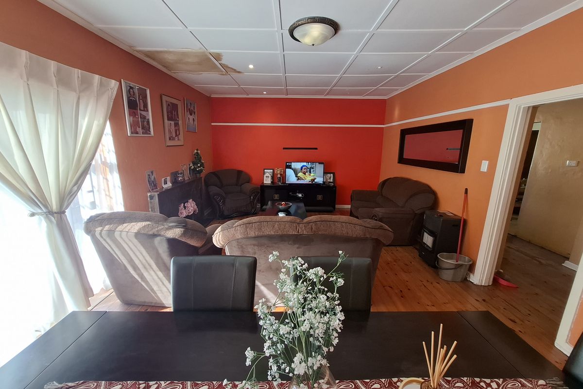 A living room featuring timber flooring and a ceiling with visible water damage, requiring maintenance and cosmetic updates.