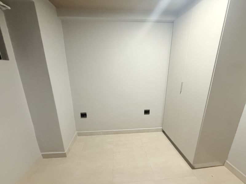 A clean, empty bedroom featuring neutral tiled flooring and a built-in wardrobe, providing a versatile space ready for personalization.