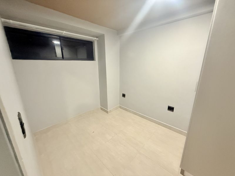 A clean, empty bedroom featuring neutral tiled flooring, a sliding window, and modern electrical outlets, ready for personalization.