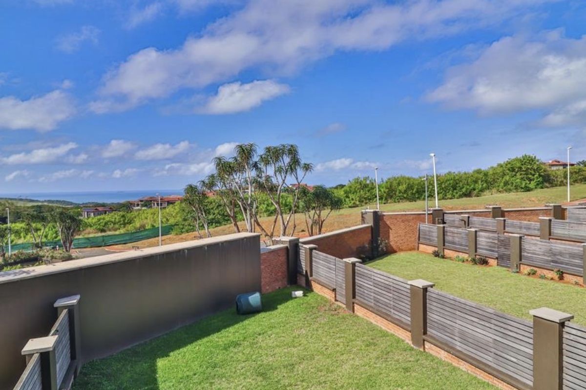 A well-maintained rear garden area featuring brick boundary walls, timber slat fencing, and a clear view of the surrounding landscape.