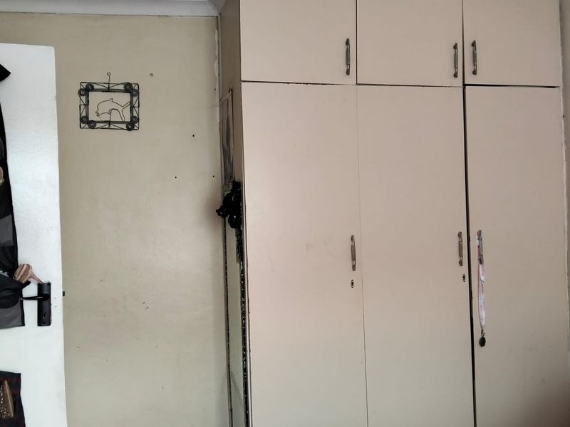 A bedroom featuring a built-in wardrobe with overhead storage cupboards and standard coving detail.