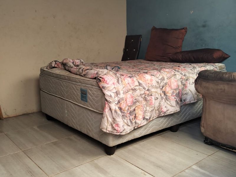 A bedroom featuring tiled flooring and exposed ceiling beams, currently requiring cosmetic updates to the wall finishes.