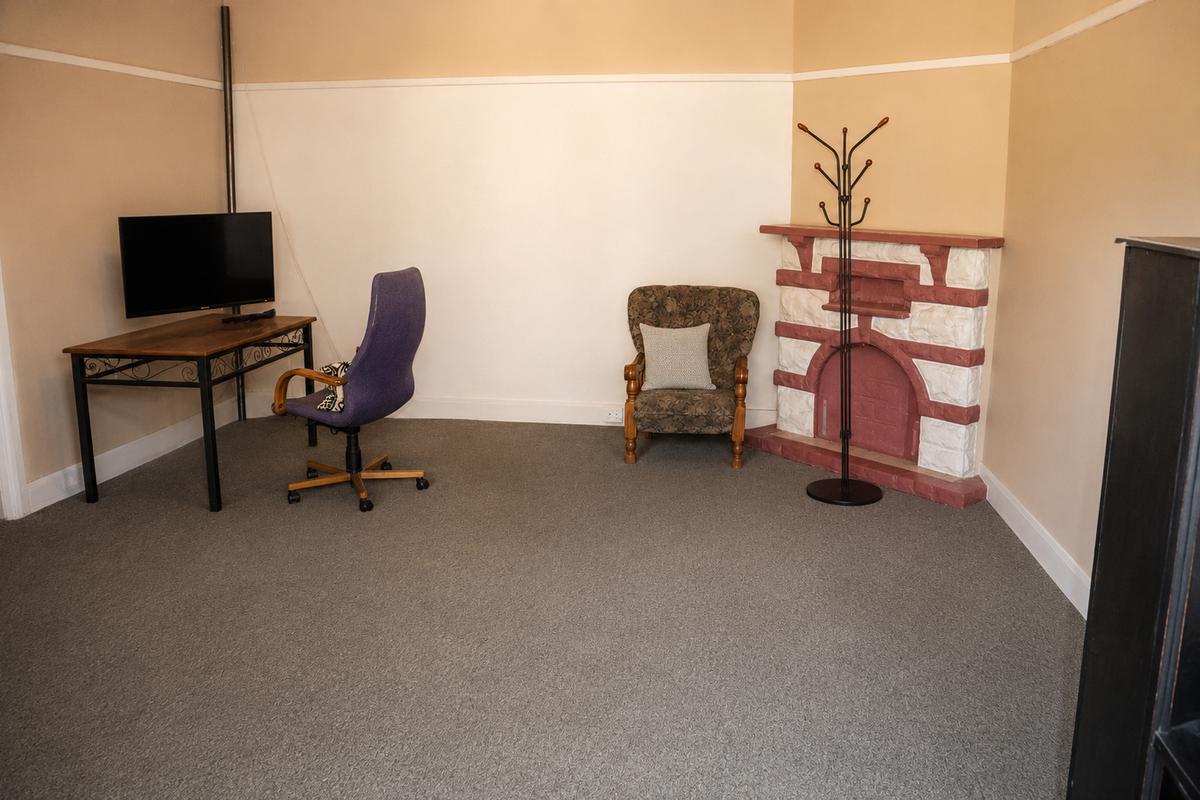 A living room featuring neutral walls, carpet flooring, and a decorative fireplace, offering a versatile space for relaxation or home office use.