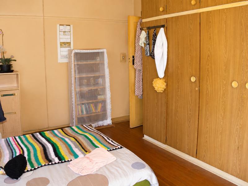 A bedroom featuring built-in wooden cupboards and laminate flooring, offering functional storage space within a neutral interior setting.
