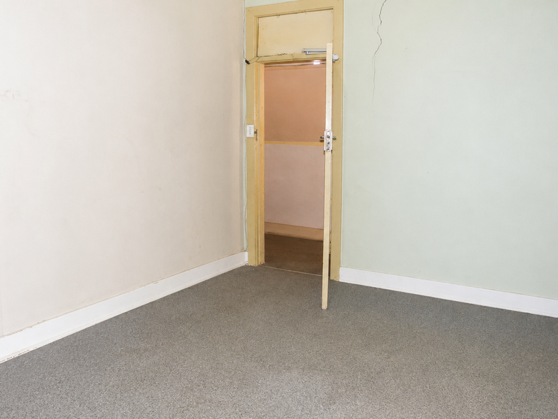 An empty bedroom featuring carpeted flooring and visible wall cracks, requiring maintenance and cosmetic updates to improve its overall condition.
